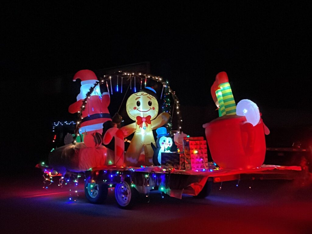 A Christmas-themed float at a holiday themed parade at night.